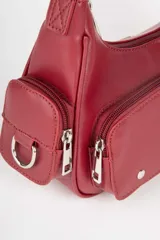 Cartera en símil cuero color burdeos con cuatro bolsillos externos, detalles de tachas y hebillas metálicas.