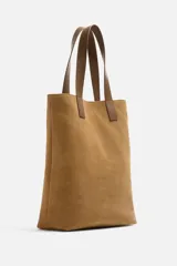 Bolso tipo shopper color marrón claro, fabricado en cuero con acabado serraje. Tiene doble asa de mano de cuero y un bolsillo interior con cierre.