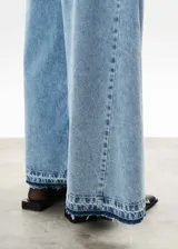 Pantalón de jean celeste de corte mega wide, con cintura alta y ruedo desflecado.