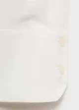 Camisa blanca de corte clásico, manga larga con puños abotonados, cuello camisero y cierre frontal con botones.