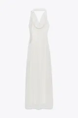 Vestido largo de tejido rústico color blanco, con escote fluido tipo halter y bufanda integrada. Espalda descubierta y forro corto interior.