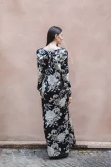 Vestido largo de seda color negro con estampado de flores blancas, palmeras y tigres. Tiene escote en V, mangas largas y lazo en la espalda.