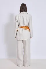 Blazer color crema de lino con corte clásico, solapas de muesca y cierre cruzado con un botón. Incluye un pañuelo de seda estampado atado a la cintura.