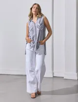 Blusa sin mangas con estampado a rayas verticales en tonos grises y blancos. Tiene cuello camisero, cierre frontal con botones y dos bolsillos con solapa en el pecho.