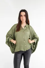 Camisa color beige de satén con corte holgado, cuello camisero y mangas largas con puños abotonados.