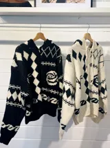 Camperón tejido oversize con capucha, bolsillos y estampa de ciervo.