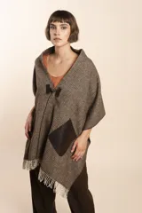 Chal de lana fina sin teñir, con calce en hombros, abrochadura con alamar de fieltro, bolsillos de cuero y terminación con flecos. Diseño exclusivo de Don Baez, hecho en Uruguay.