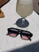 Lentes de sol de mujer con armazón grueso de policarbonato color rosa translúcido y lentes oscuros degradados. Diseño de montura geométrica con puente doble.