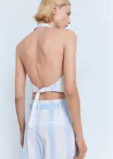 Top tipo chaleco con cuello halter y cierre frontal de tres botones. Presenta un diseño entallado con rayas verticales celestes y blancas, dos bolsillos frontales de ribete y ajuste de hebilla en la espalda.