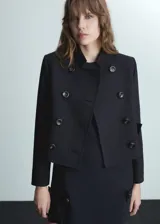 Chaqueta crop de color negro, con cierre de doble botonadura y cuello de tira.