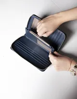 Billetera negra de cuero con cierre de cremallera, múltiples ranuras para tarjetas, compartimento para billetes y monedero con cremallera.