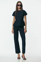 Top azul marino de punto con cuello redondo y manga corta. Tiene corte a la cintura y peplum en el bajo.