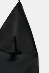 Vestido midi de seda color crema, con escote pronunciado en pico y tirantes finos ajustables tipo halter. El bajo es asimétrico y está adornado con un delicado encaje a tono.