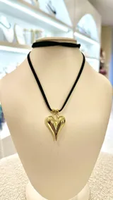 Gargantilla con dije de corazón dorado y tiento de gamuza negro.