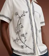 Camisa de manga corta confeccionada en algodón y lino, color blanco con bordado floral en negro.