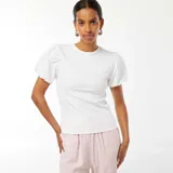 Camiseta blanca de punto con cuello redondo y mangas cortas abullonadas.