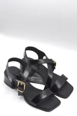 Sandalias negras con tiras cruzadas, hebilla dorada y taco ancho.