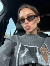 Lentes de sol negros con forma ovalada y marco grueso.