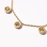 Pulsera dorada de cadena fina con siete dijes circulares con incrustaciones de cristal.