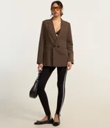 Blazer marrón de poliéster y viscosa, de corte amplio y estructura de sastrería, con solapas en el cuello, doble abotonadura, bolsillos falsos y pinzas.