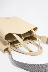 Bolso tote negro de cuero vacuno con doble asa corta y correa de tela extraíble. Interior con tres compartimentos y bolsillo con cremallera. Logo metálico de la marca en el frente.