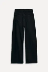 Pantalón de jean negro de corte amplio, tiro alto, con trabillas y cinco bolsillos. Cierre frontal con cremallera y botón metálico.