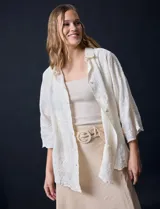 Camisa color crudo con bordado tipo broderie, cuello con solapa, manga tres cuartos y cierre frontal con botones.