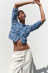 Chaqueta de punto azul y blanco con cuello redondo y manga francesa. Tiene bolsillos delanteros de plastrón y cierre frontal con botones a tono.
