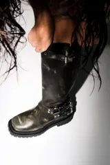 Bota alta de cuero negro con suela track, caña alta con hebilla superior y doble hebilla inferior.