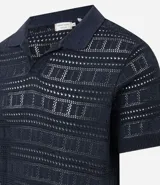 Remera polo de hombre color beige, con cuello en V, mangas cortas y textura patchwork calada.