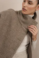 Capa marrón de lana con cuello alto abotonado y aberturas laterales.