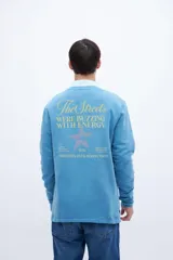 Buzo celeste de felpa liviana con cuello redondo, puños en mangas y bajo holgado. Tiene un bordado pequeño en el pecho con la inscripción "Uniform St.".