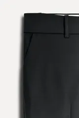 Pantalón de vestir negro de lana con corte recto, tiro bajo, trabillas para cinturón, bolsillos laterales y traseros de doble vivo.