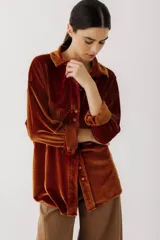Camisa beige de terciopelo con cuello clásico, cierre frontal con botones, dos bolsillos de parche en el pecho y mangas largas con puños abotonados.