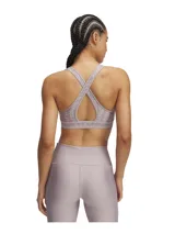 Top deportivo Under Armour con estampado floral en tonos rosa y amarillo sobre fondo negro. Cuenta con tirantes cruzados en la espalda y banda elástica con el logo de la marca en el contorno inferior.