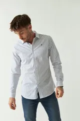 Camisa de hombre a rayas verticales celestes y blancas, corte slim fit, manga larga, logo bordado en el pecho y cartera con botones.