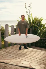 Remera verde con estampa en la espalda con texto "Glassy Waves Club" y dibujo de palmeras y una ola.