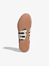 Zapatillas Adidas Taekwondo Mei sin cordones, con capellada de cuero vacuno con estampado animal print de vaca, las tres tiras características de la marca en cuero blanco y suela de goma color caramelo.