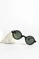 Lentes de sol con montura redonda negra y cristales verdes.