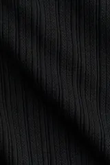 Top ajustado de punto acanalado suave, color negro, con cuello alto y mangas largas acampanadas.