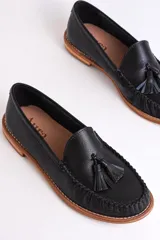 Mocasines plateados de cuero con detalle de borlas y costuras en contraste.