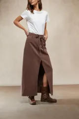 Falda larga de mezclilla color marrón chocolate, de tiro alto con cordón ajustable en la cintura y abertura frontal pronunciada.