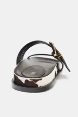 Sandalias planas con estampado animal print de piel con pelo. Cierre mediante hebilla en efecto metalizado. Acabado en punta redonda.