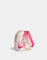 Llavero y charm de mochila color rosa claro, con estampado de productos de maquillaje y tiracierre metálico en forma de corazón dorado.