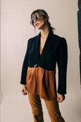 Blazer negro con solapas y cierre con botón de madera. Presenta corte a la cintura y parte inferior color marrón.