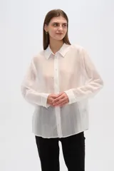 Camisa blanca traslúcida de lyocell, corte holgado, con cuello camisero, cierre frontal con botones y mangas largas con puños abotonados.