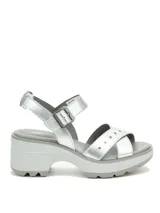 Sandalia plateada con tiras cruzadas y detalles de tachas, sujeción con hebilla al tobillo y plataforma con suela dentada.