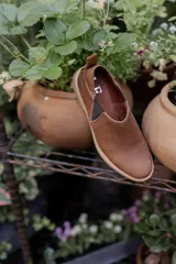 Mocasines marrones de cuero con elásticos laterales y tirador trasero.