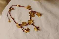 Collar corto con cordón de algodón color menta y flores de bronce.