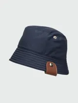 Sombrero tipo bucket reversible, negro de un lado y beige del otro, con detalle de cuero marrón con botón metálico en el lateral.